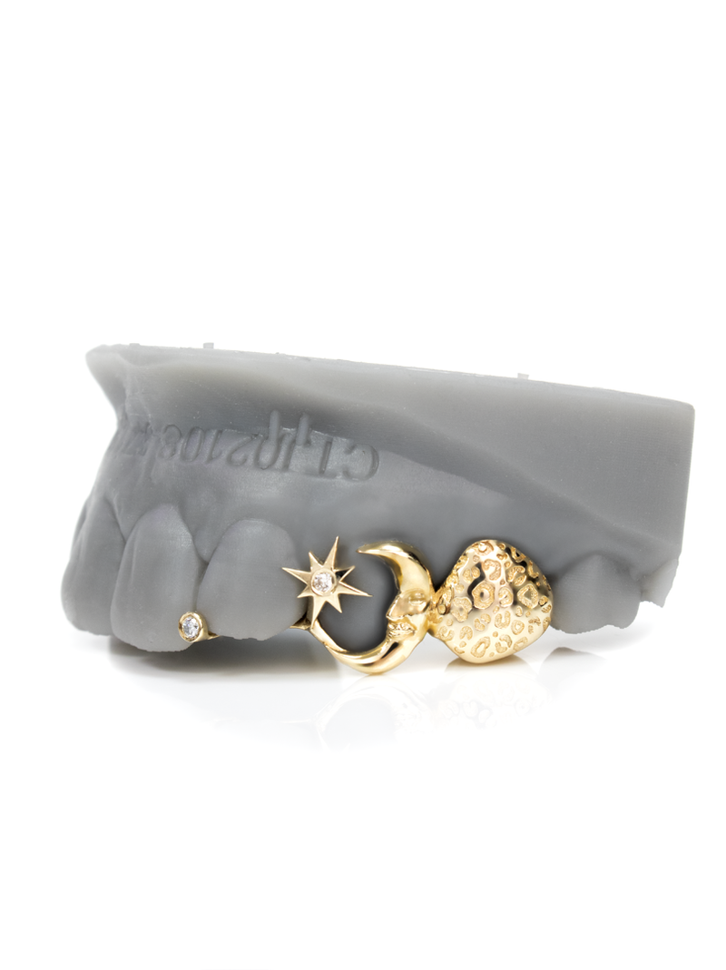 Solid gold grillz with stone-set star, crescent moon and textured nugget heart, plus a bezel-set diamond cap